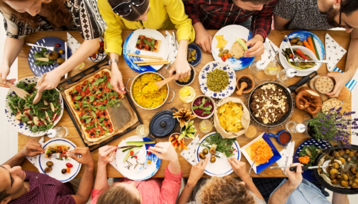 Personas comiendo un banquete sentados en una mesa